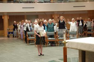 Sister Katherine, holding a copy of the Adrian Dominican Sisters’ Constitution, receives the blessings of the assembly.