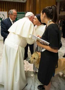 The Holy Father gives Sr. Pauline a kiss. Her dog, Pax, is at her side, and her translator.